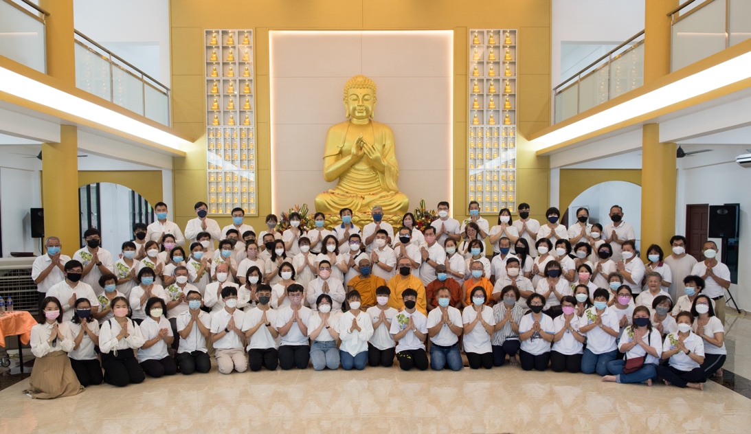 A group of people posing for a photo in front of a golden statue

Description automatically generated